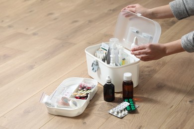 Photo of Woman putting medicament into first aid kit indoors, closeup. Space for text