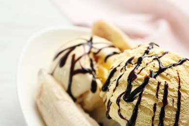 Delicious banana split ice cream with chocolate topping on plate, closeup