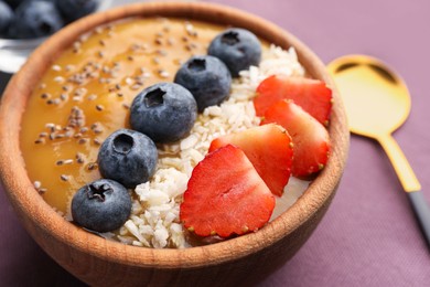 Photo of Delicious smoothie bowl with fresh berries, chia seeds and coconut flakes on table, closeup