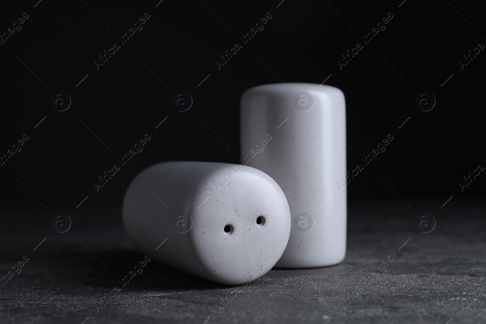 Photo of Salt and pepper shakers on dark textured table