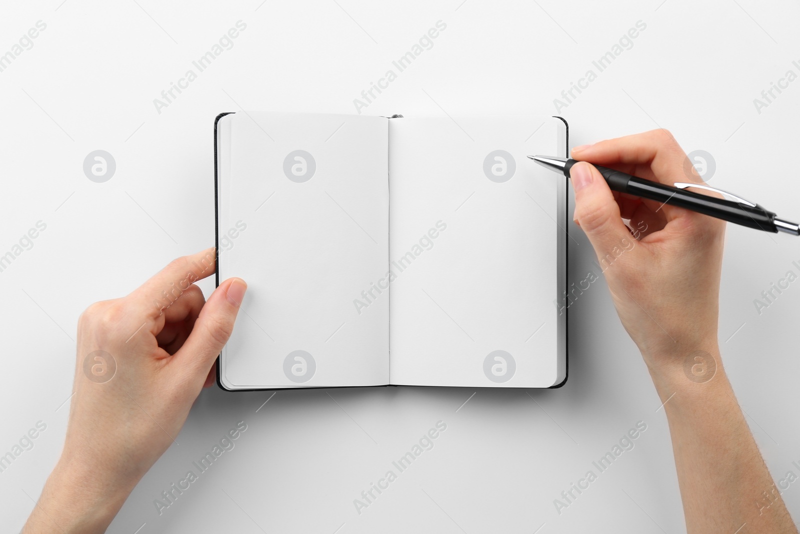 Photo of Woman writing in notebook on white background, top view