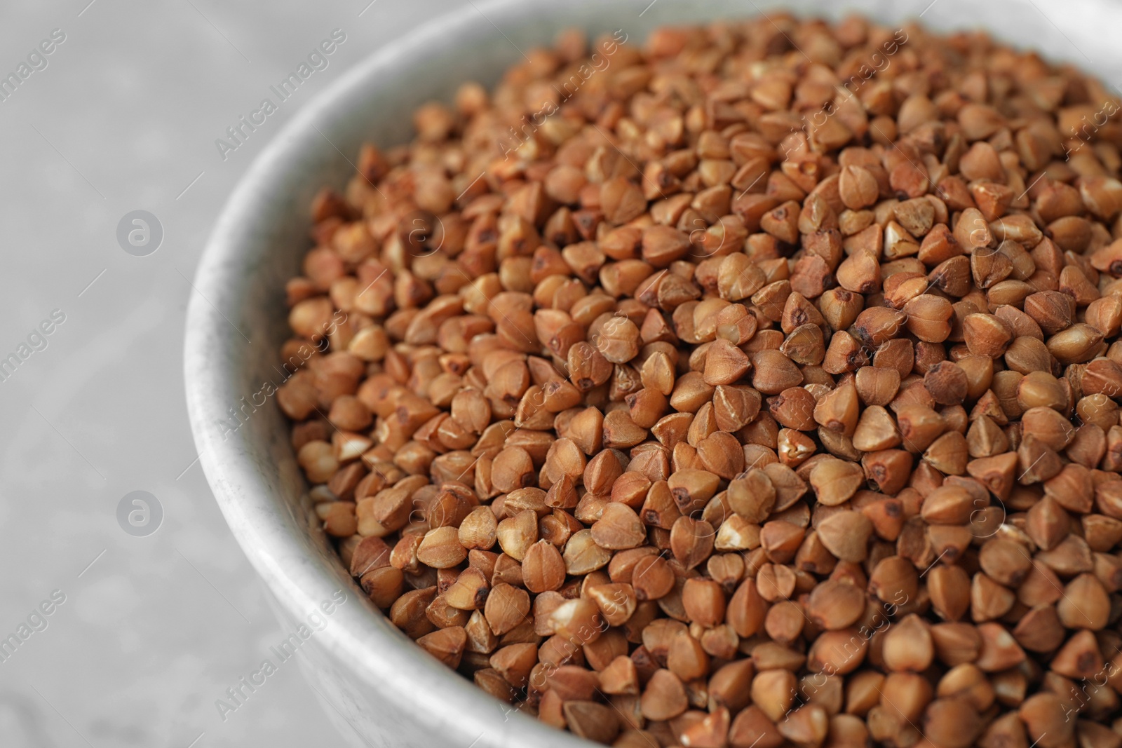 Photo of Uncooked buckwheat in bowl on table, closeup