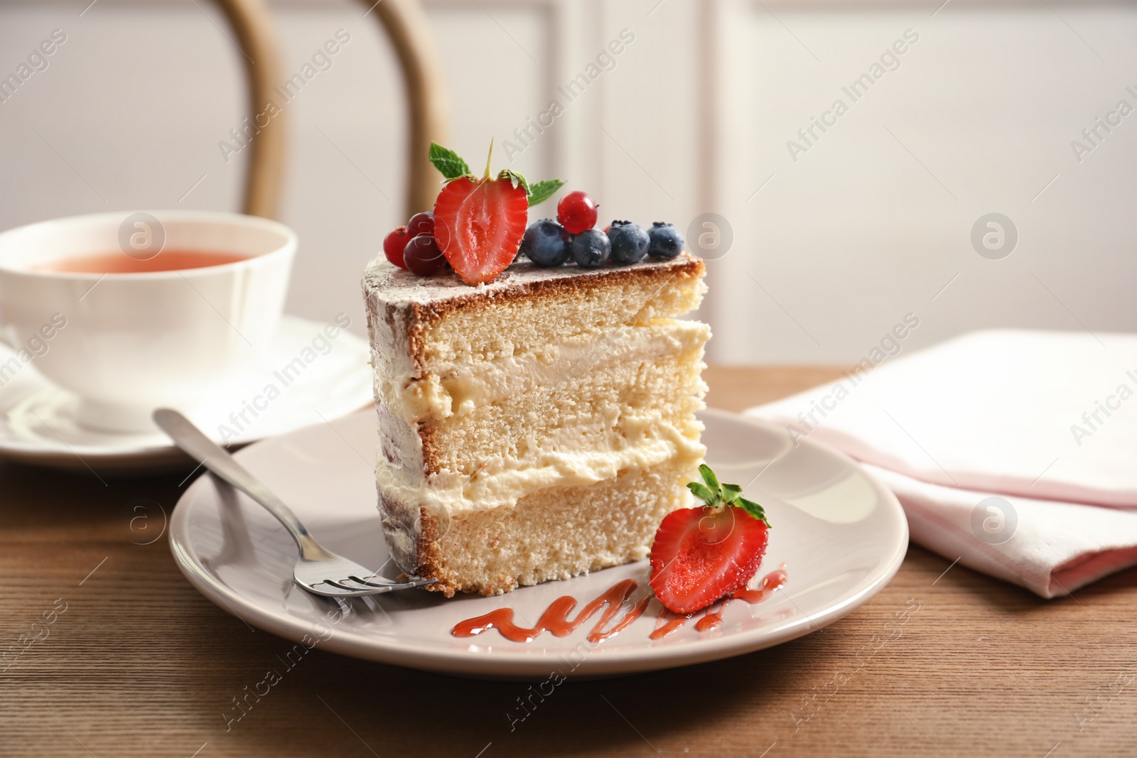 Photo of Piece of delicious homemade cake with fresh berries served on wooden table