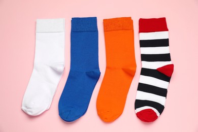 Photo of Different colorful socks on pink background, flat lay