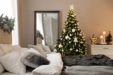 Photo of Festive bedroom interior with decorated Christmas tree