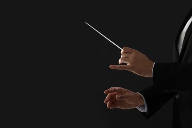 Professional conductor with baton on black background, closeup. Space for text