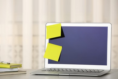 Laptop with empty sticky notes and stationery on table indoors. Space for text