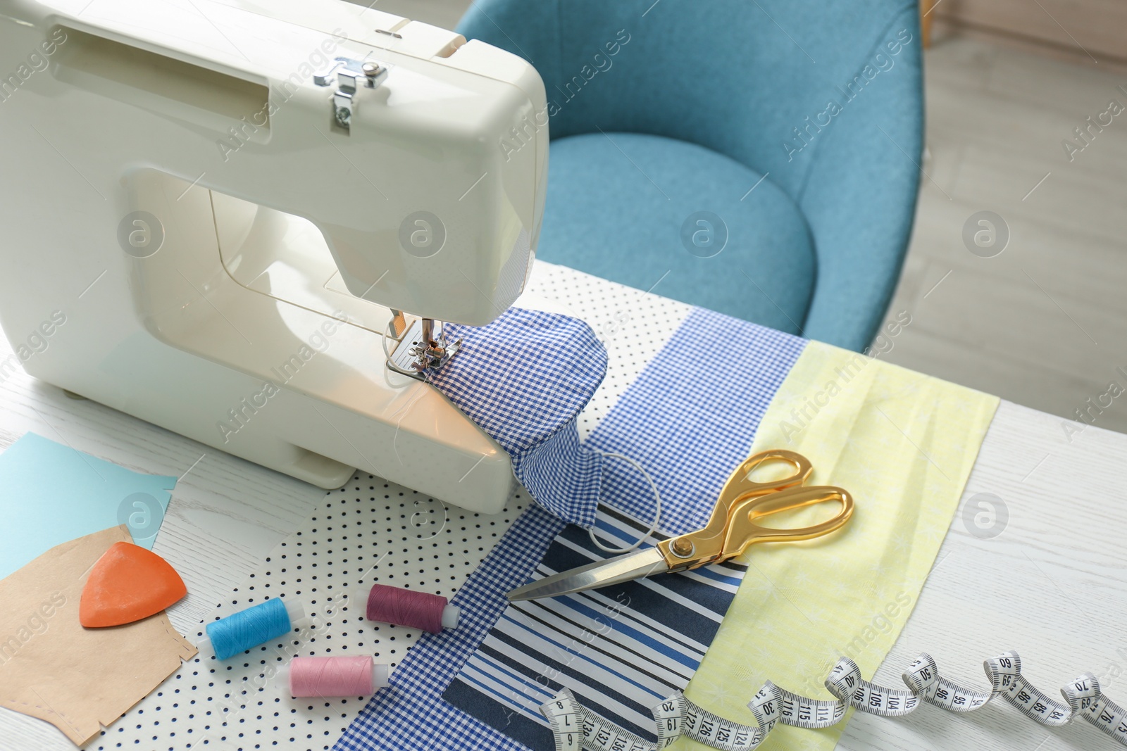 Photo of Sewing machine, craft accessories and cloth mask on table. Personal protective equipment during COVID-19 pandemic