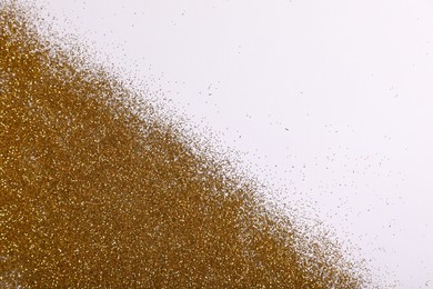 Shiny golden glitter on white background, top view