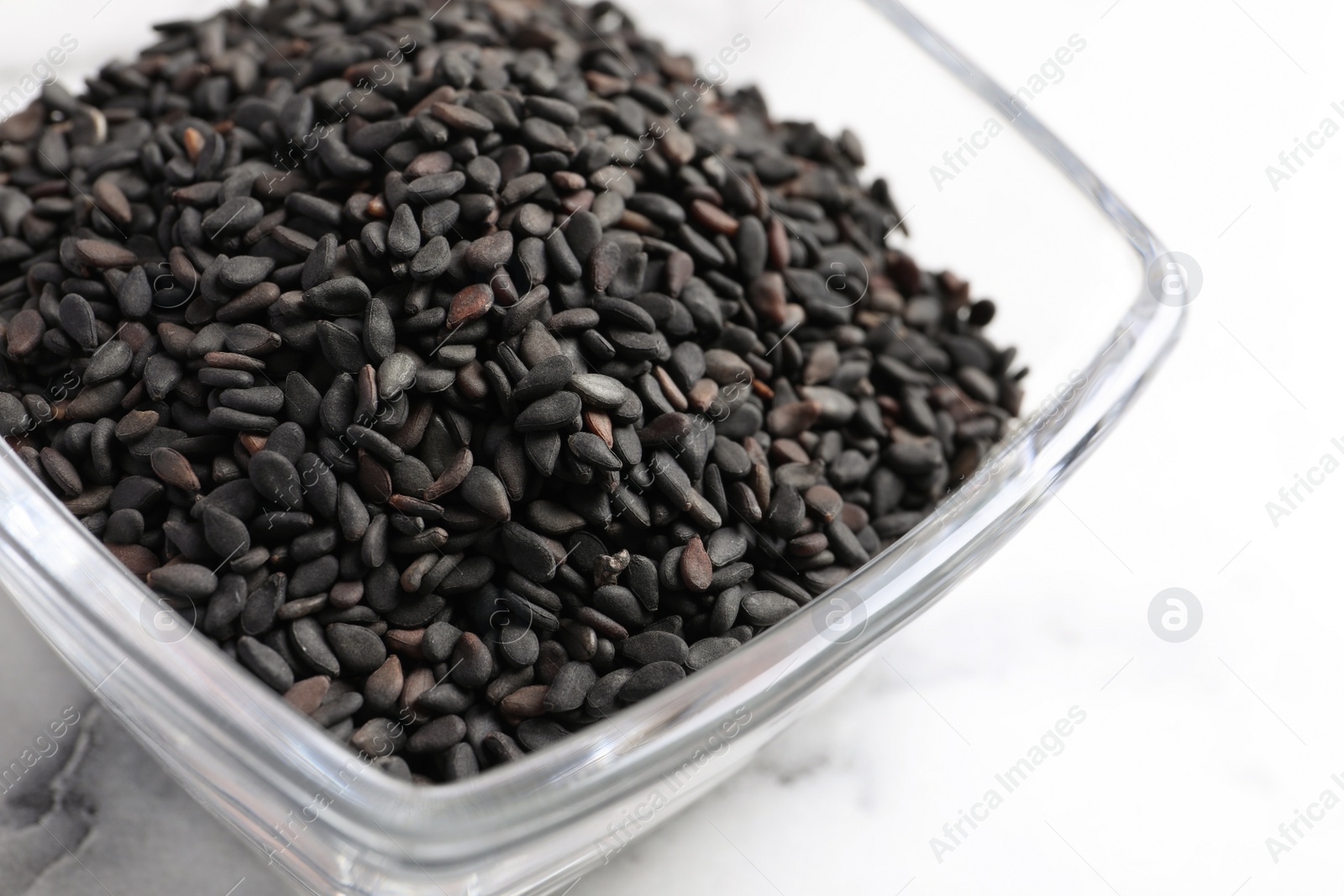 Photo of Black sesame seeds on white marble table, closeup