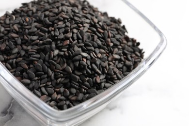 Photo of Black sesame seeds on white marble table, closeup