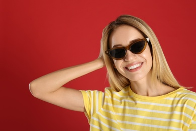 Photo of Beautiful woman in stylish sunglasses on red background