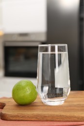 Photo of Filtered water in glass and lime on table in kitchen, closeup