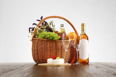 Picnic basket with wine and products on wooden table against white background