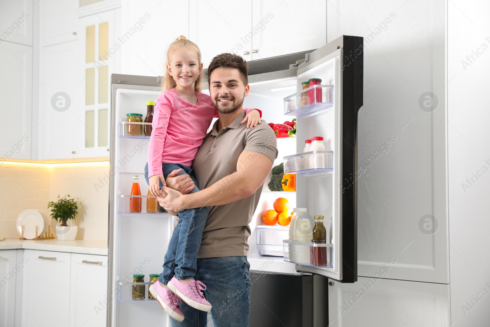 Photo of Young father with daughter near open refrigerator in kitchen