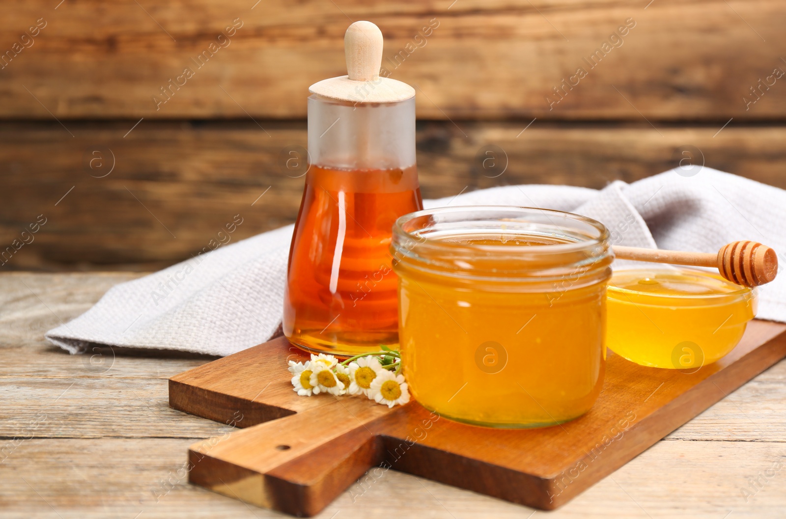 Photo of Different tasty honey and chamomile flowers on wooden table