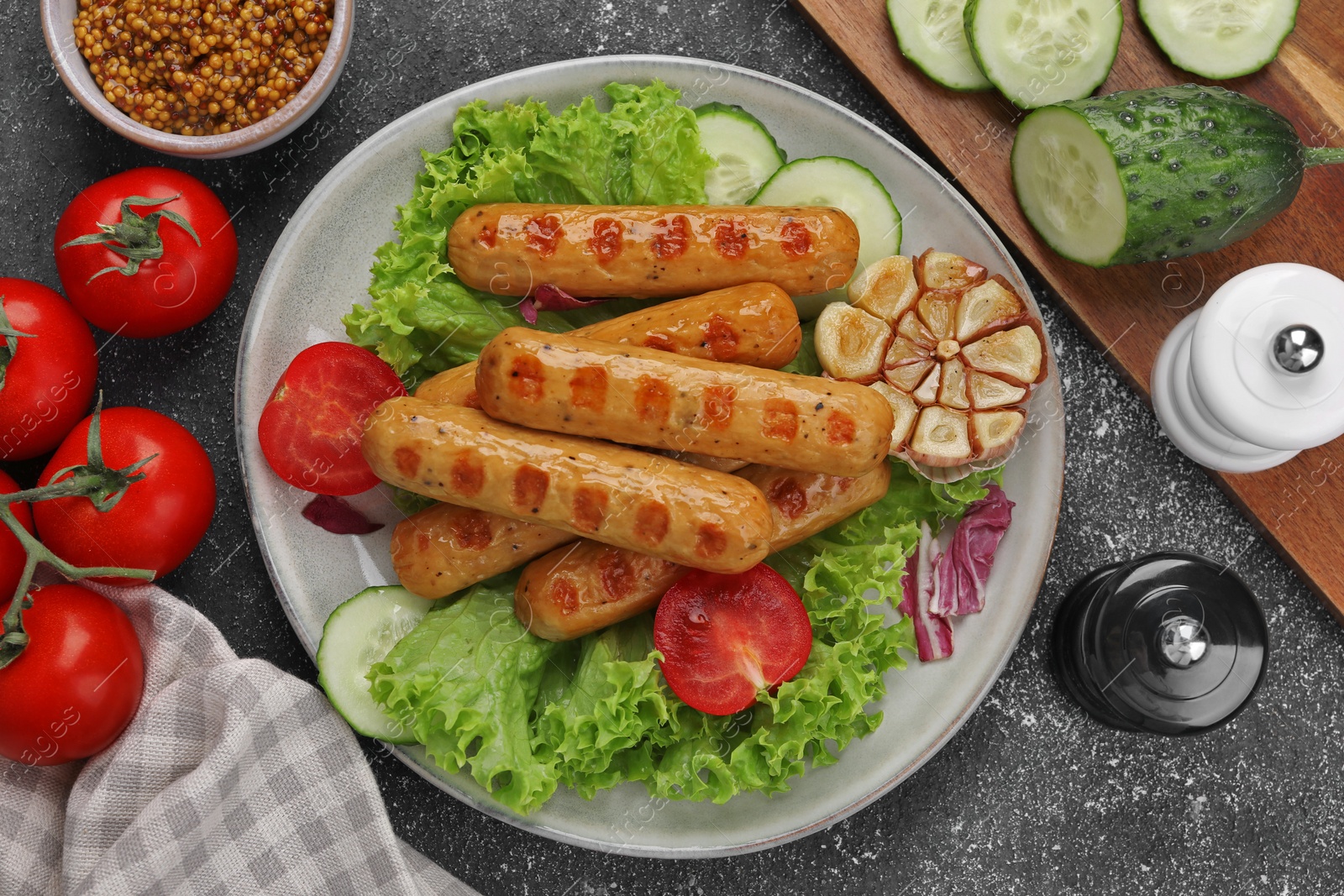 Photo of Delicious grilled vegan sausages with fresh herbs and vegetables on grey table, flat lay