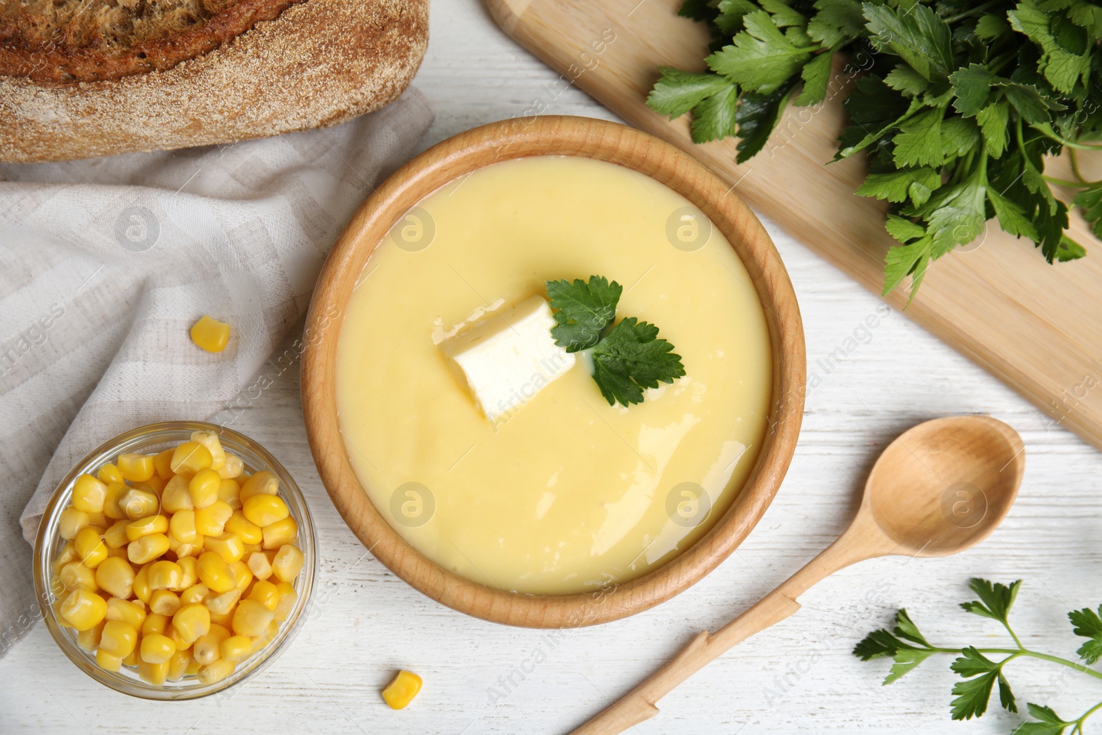 Photo of Delicious corn cream soup served on white wooden table, flat lay