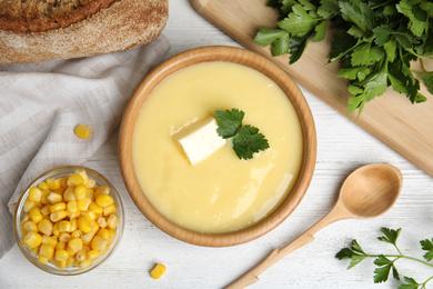 Photo of Delicious corn cream soup served on white wooden table, flat lay