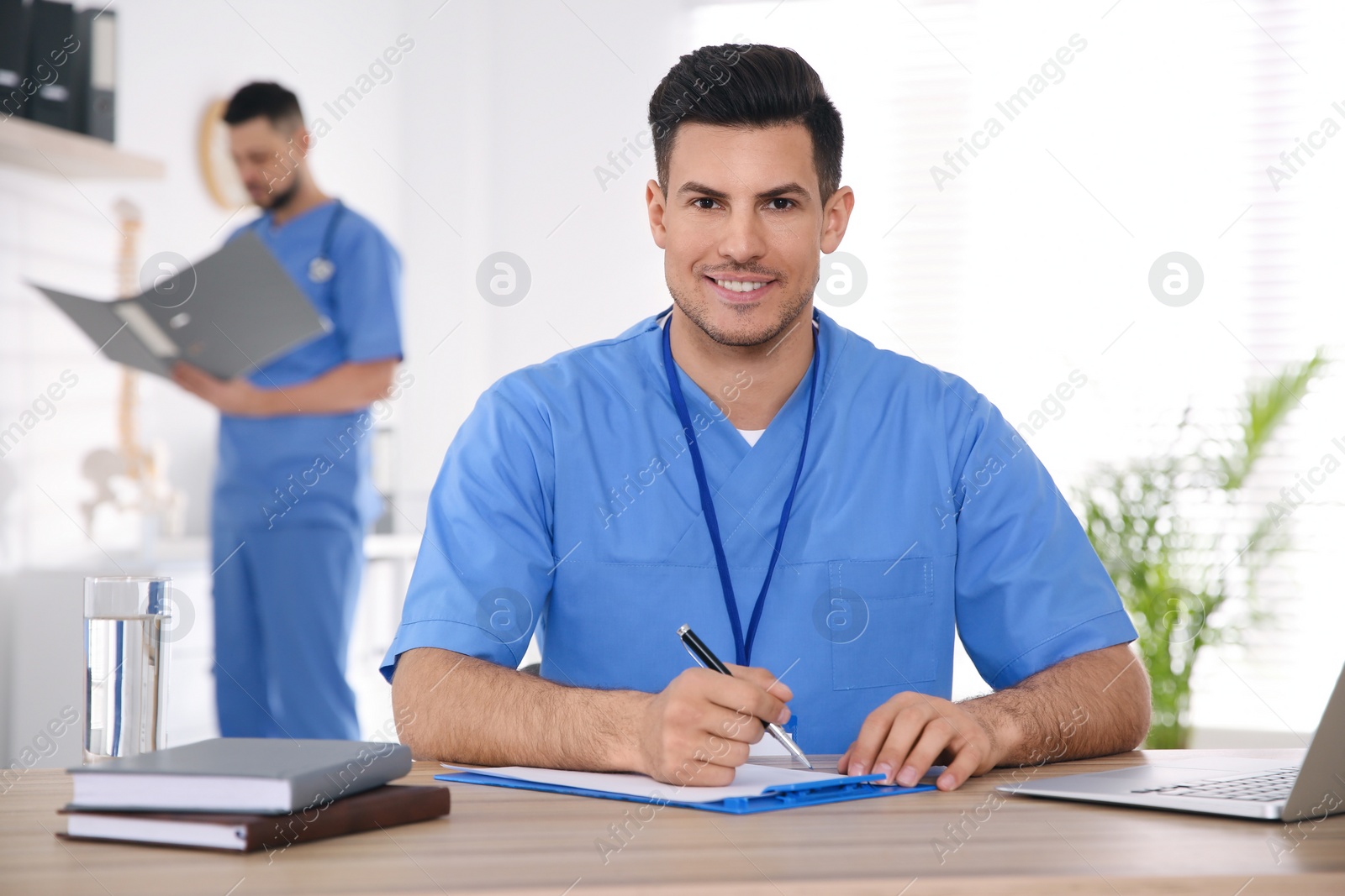 Photo of Portrait of male doctor at table in modern clinic