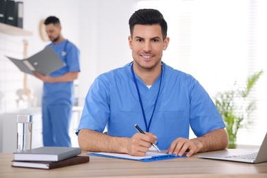 Portrait of male doctor at table in modern clinic