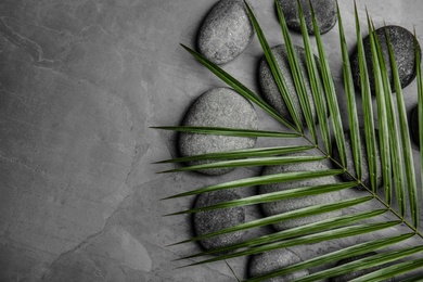 Photo of Zen stones and tropical leaf on dark background, top view with space for text