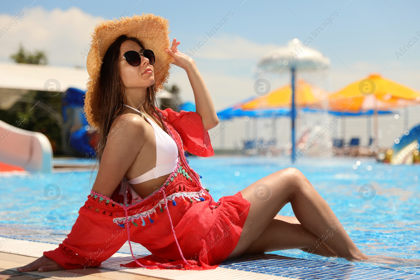 Photo of Young woman sitting near outdoor swimming pool