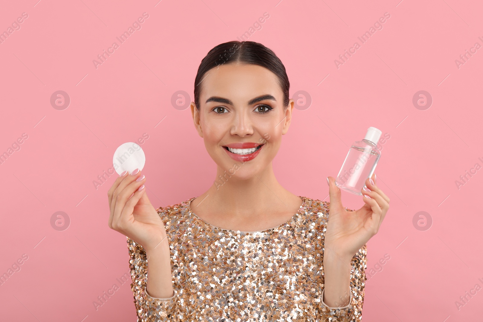 Photo of Beautiful woman removing makeup with cotton pad on pink background