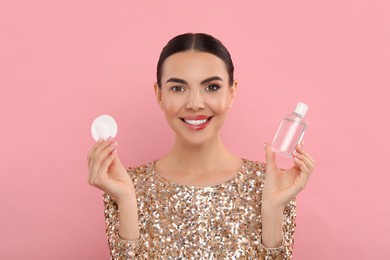 Photo of Beautiful woman removing makeup with cotton pad on pink background