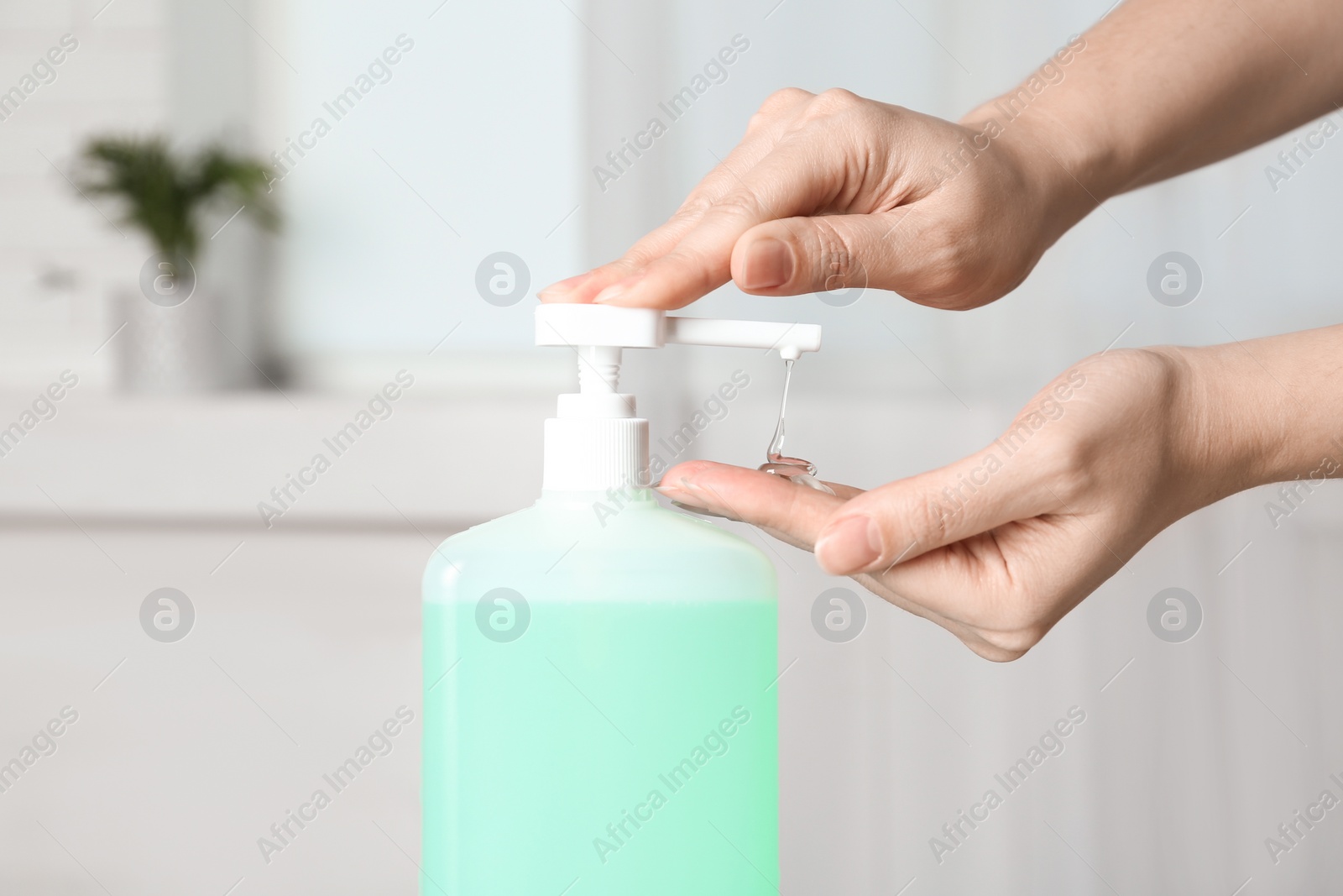 Photo of Woman applying antiseptic gel on hand indoors, closeup