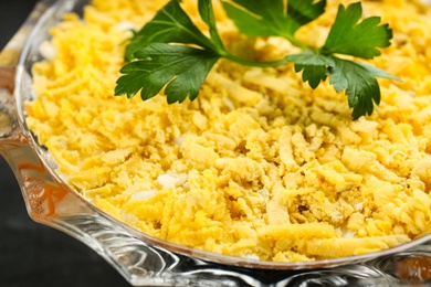 Photo of Traditional russian salad Mimosa in glass bowl, closeup