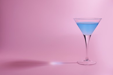 Photo of Martini glass with delicious cocktail on pink background, space for text