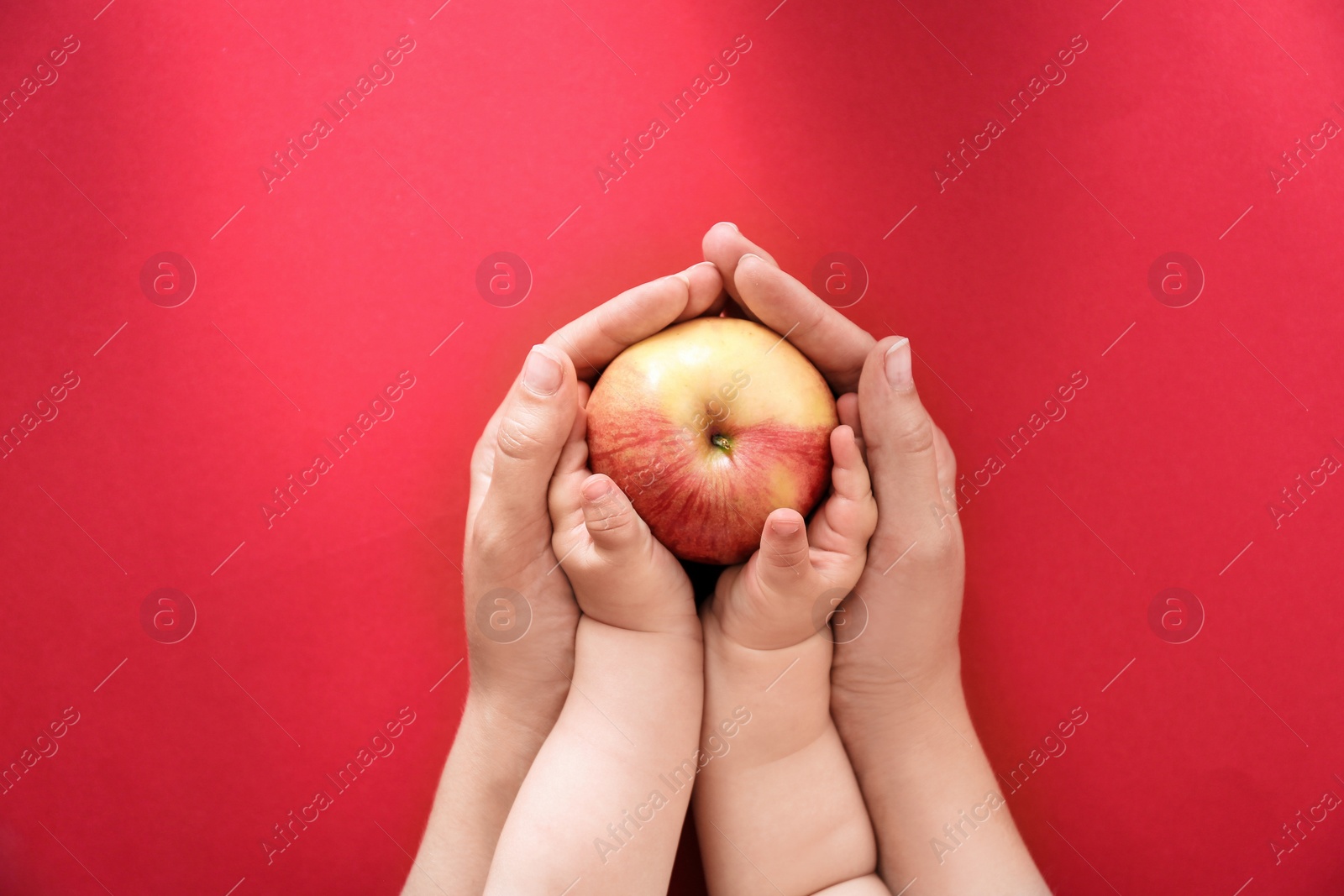 Photo of Young woman and little child holding apple on color background, top view. Healthy diet