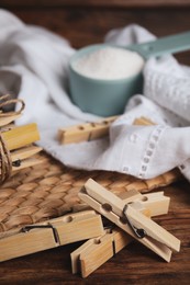 Wooden clothespins, scoop of laundry powder and fabric on table, closeup