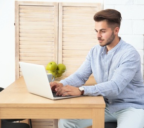 Man in casual clothes using laptop at table indoors