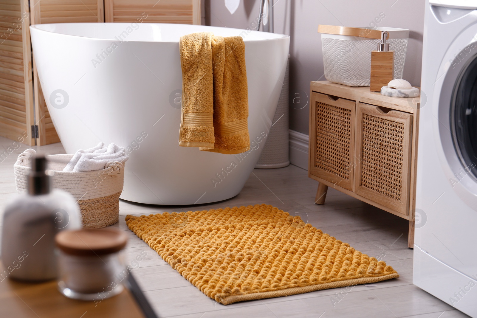 Photo of Soft orange mat on floor near tub in bathroom. Interior design