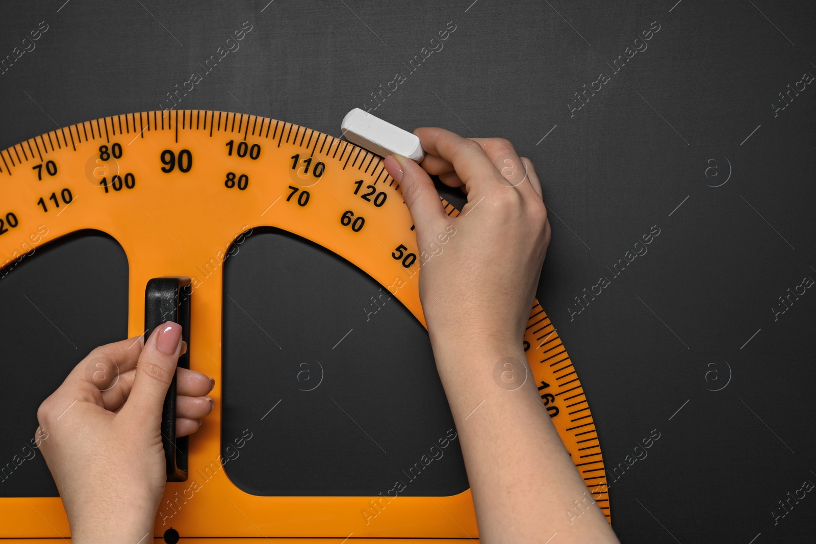 Photo of Woman drawing with chalk and protractor on blackboard, closeup