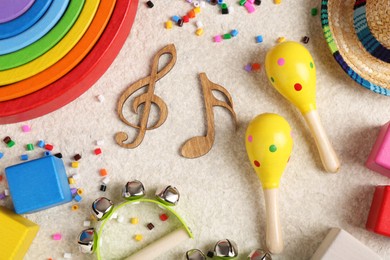 Photo of Baby song concept. Wooden notes, kids musical instruments and toys on beige carpet, flat lay