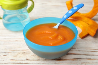 Photo of Bowl of healthy baby food on wooden table