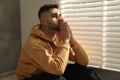 Photo of Sad young man and sitting near window