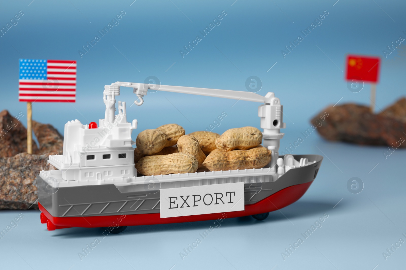 Photo of Toy cargo vessel, stones with American and Chinese flags on color background. Export concept