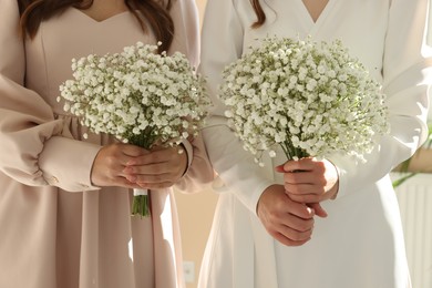 Photo of Bride and her bridesmaid with beautiful bouquet indoors, closeup. Wedding day