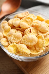 Bowl of tasty corn flakes on wooden table, closeup
