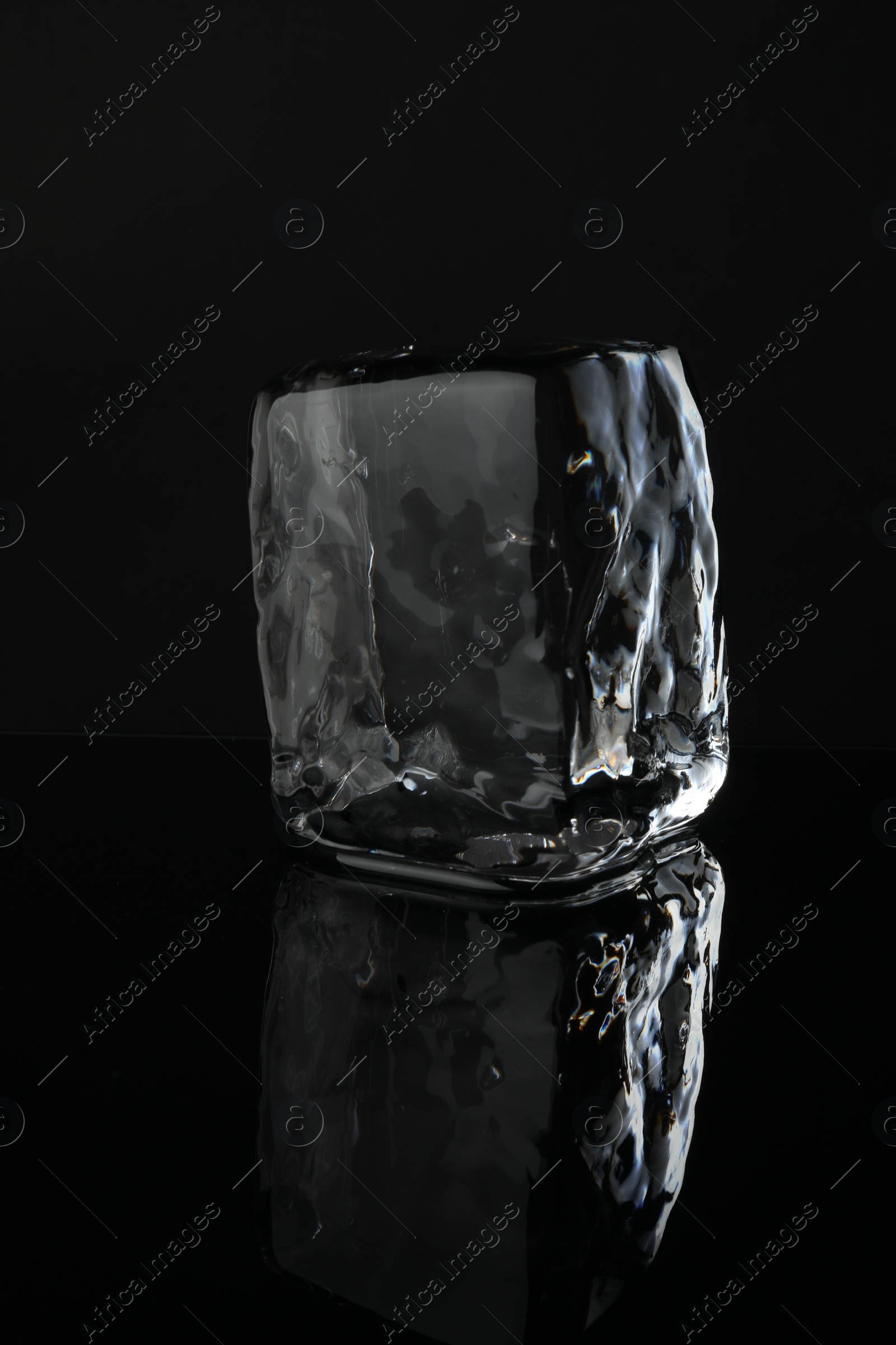 Photo of One cube of clear ice on black mirror surface