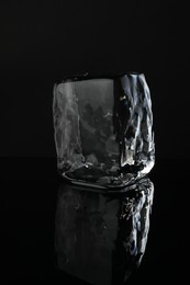 Photo of One cube of clear ice on black mirror surface