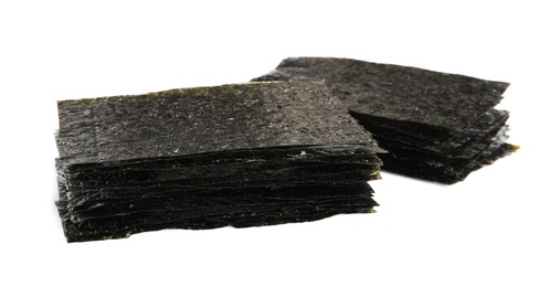 Photo of Stacks of dry nori sheets on white background