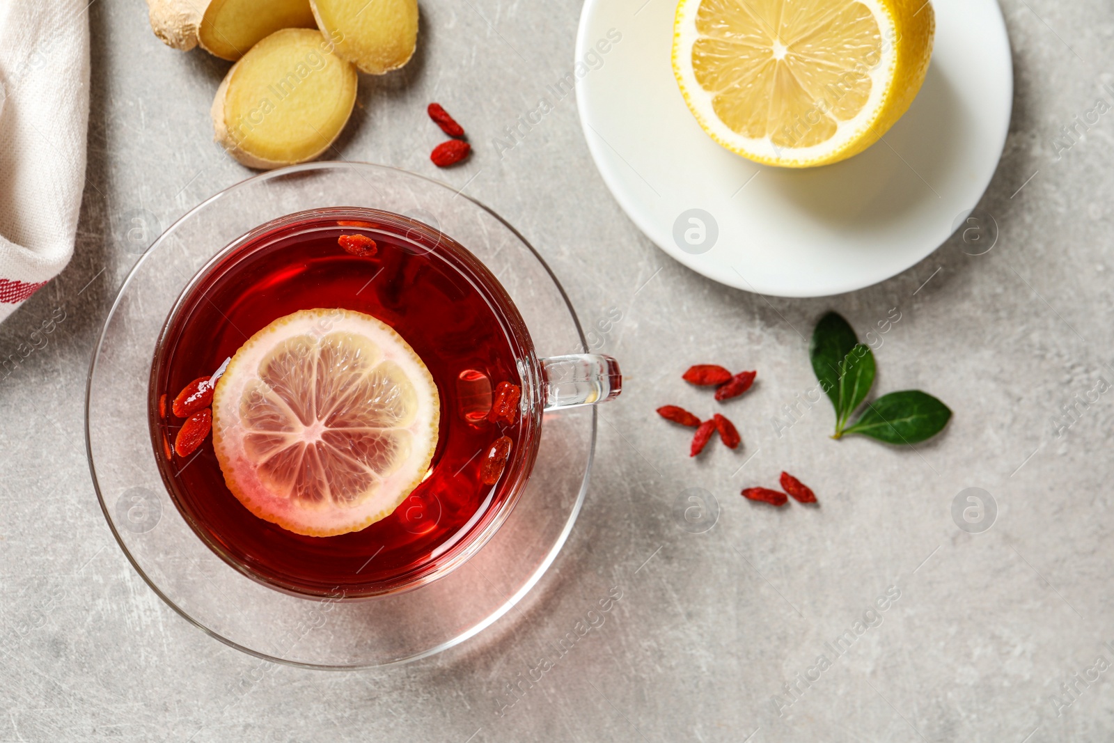 Photo of Flat lay composition with cup of healthy goji tea on grey table