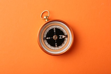 Photo of One compass on orange background, top view