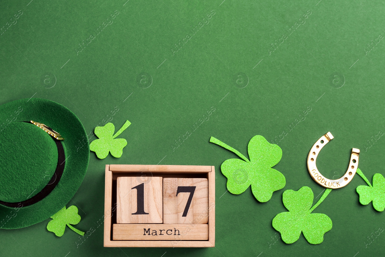 Photo of Leprechaun's hat, block calendar and St. Patrick's day decor on green background, flat lay. Space for text