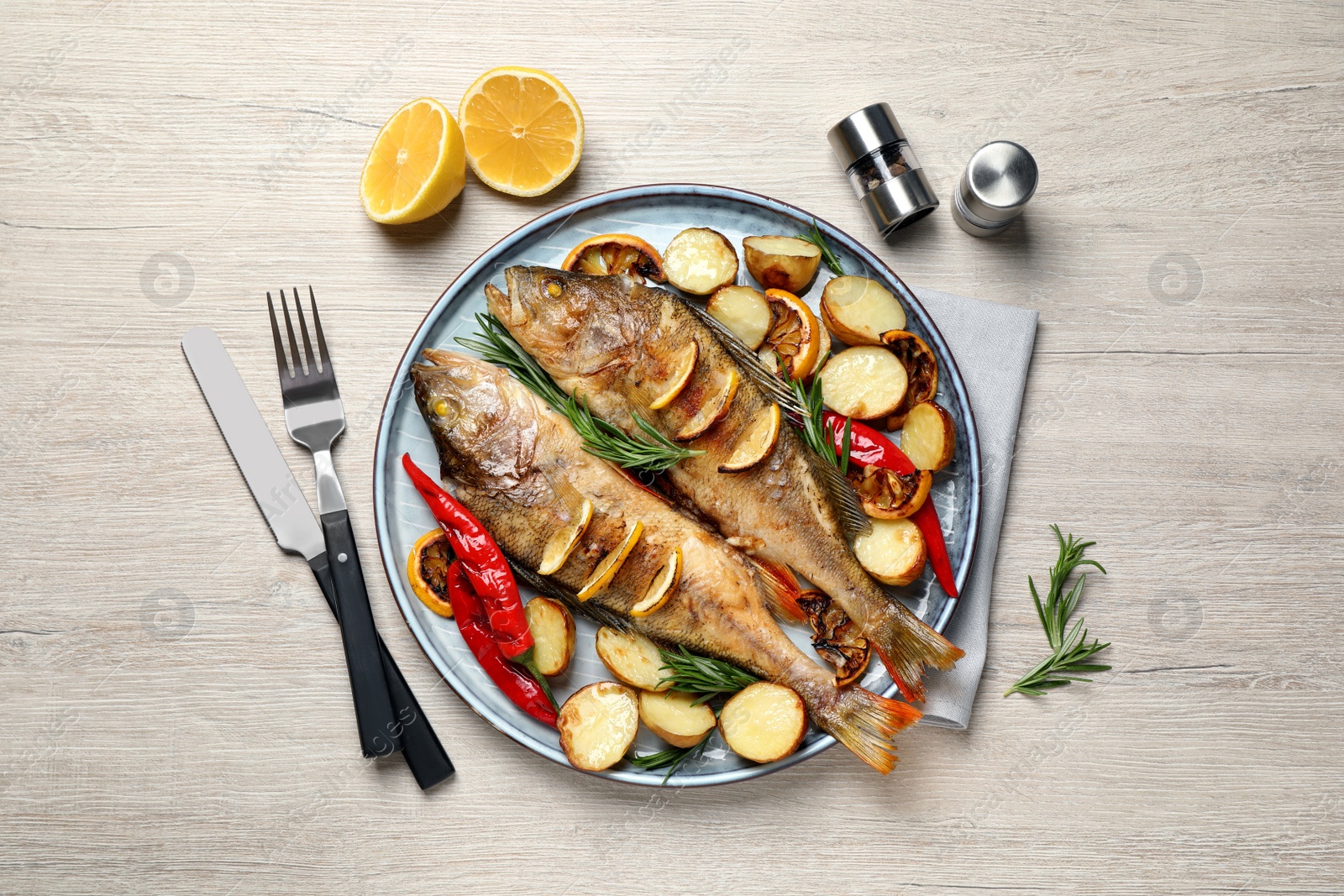 Photo of Tasty homemade roasted perches served on wooden table, flat lay. River fish